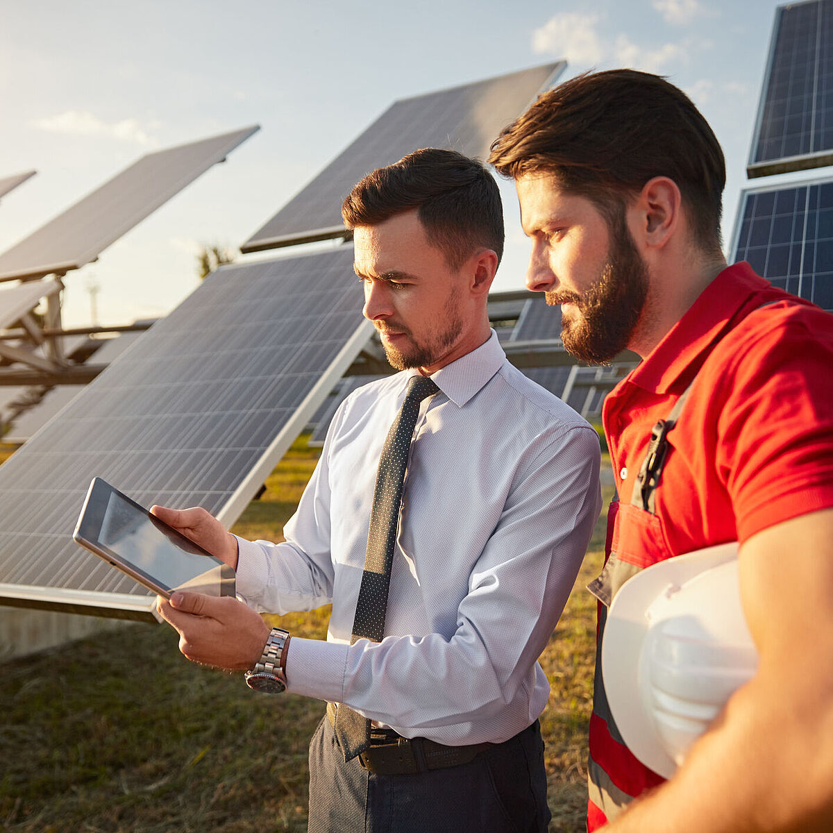 Zwei Personen diskutieren über einem Dokument, im Hintergrund sind Solaranlagen zu sehen