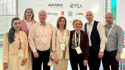 A group picture of the project partners in front of a large roll-up showing all the partner logos of the Maritime Week in Singapore.