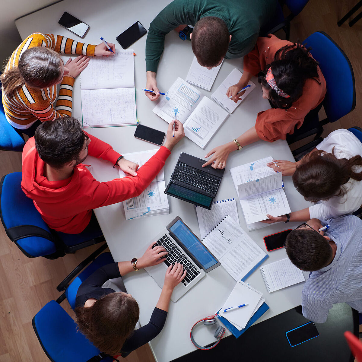 Introduction_Image Studiengang Wirtschaftsrecht Master Studierende sitzen um einen Tisch herum auf dem Unterlagen verstreut sind, Draufsicht
