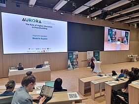 The conference room, with a view of the stage and large screens as seen from the lecture area.